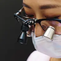 A dentist wearing magnifying loupes, focused during treatment