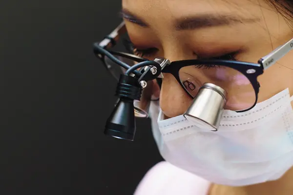 A dentist wearing magnifying loupes, focused during treatment