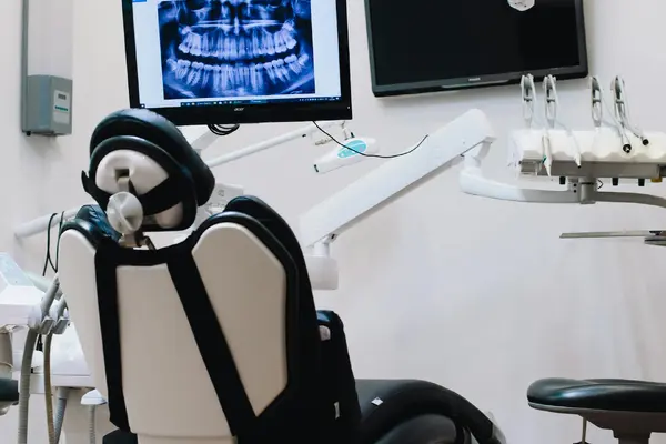 A modern dental surgery with a chair and a panoramic dental X-ray on screen