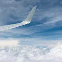 An airplane wing above the clouds in a blue sky
